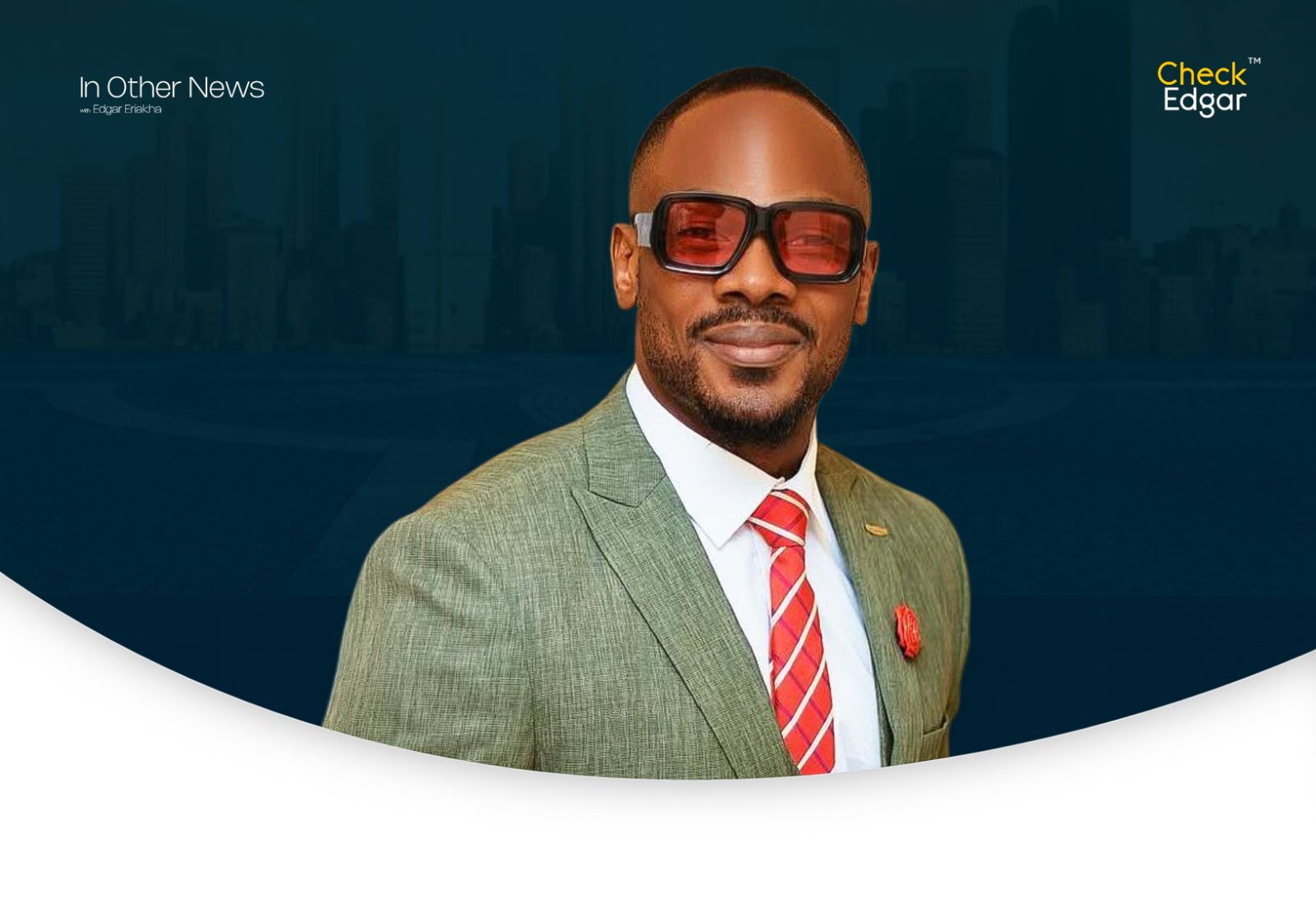 Daniel Etim in stylish sunglasses and a green suit smiles at the camera.