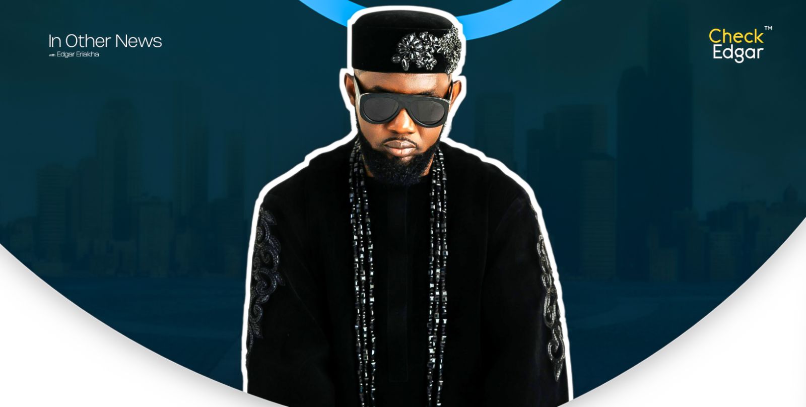 AY in sunglasses and a black outfit with intricate designs.