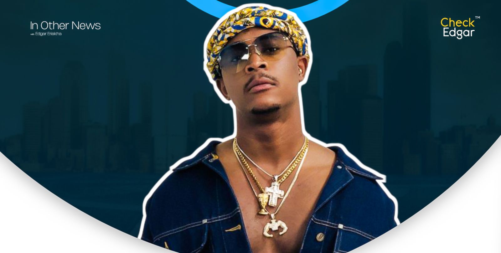 Ojay Wright wearing sunglasses and a patterned headwrap, adorned with gold chains, poses confidently.