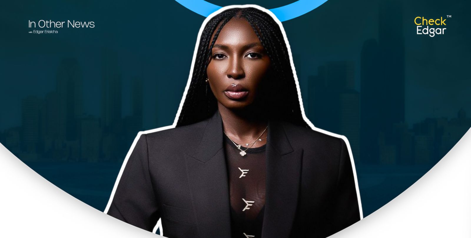 Ifedayo with long hair wearing a black suit and layered necklaces.