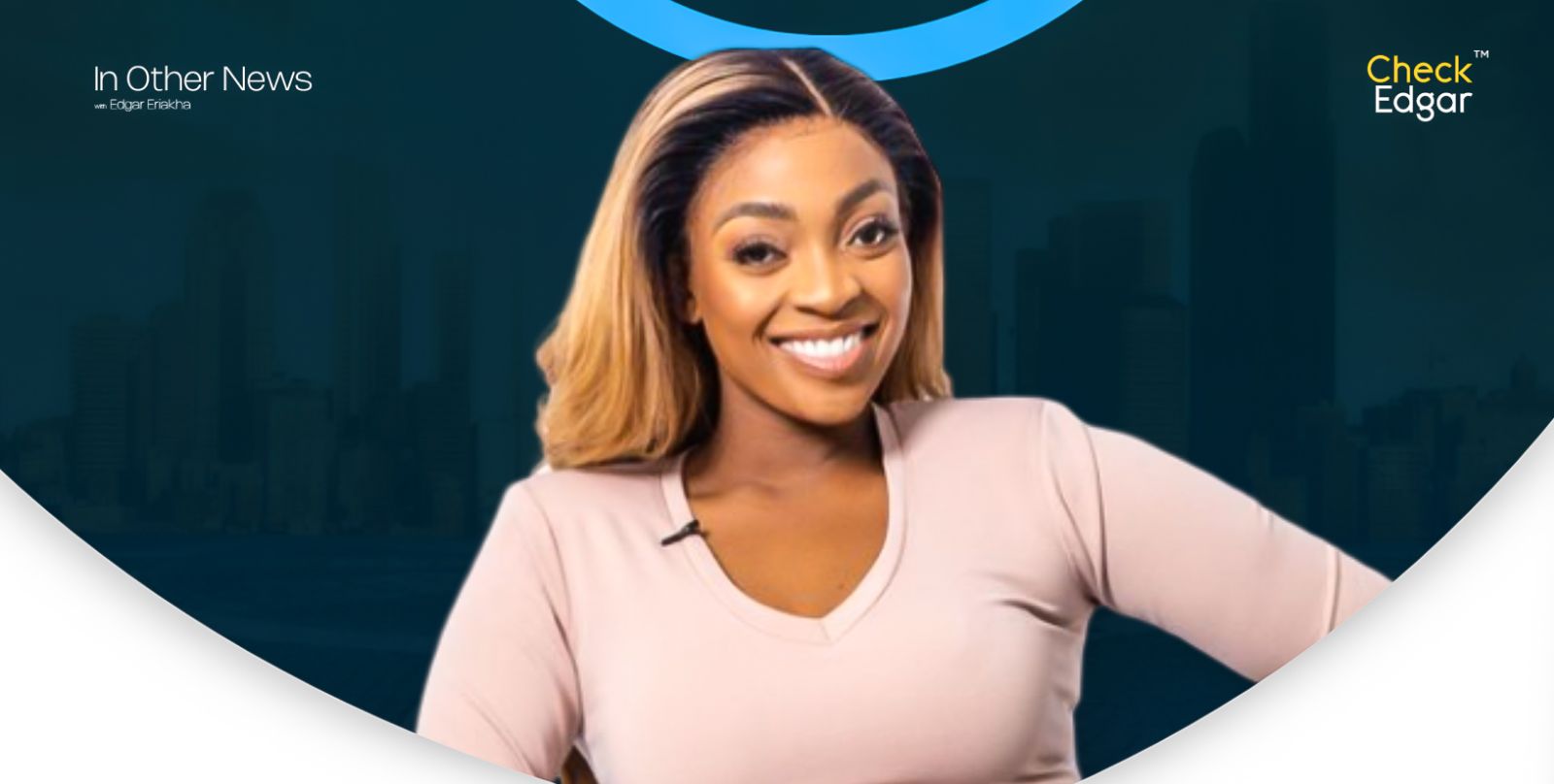 Sharon Ademefun with long, wavy hair smiles warmly at the camera, wearing a light-coloured top.