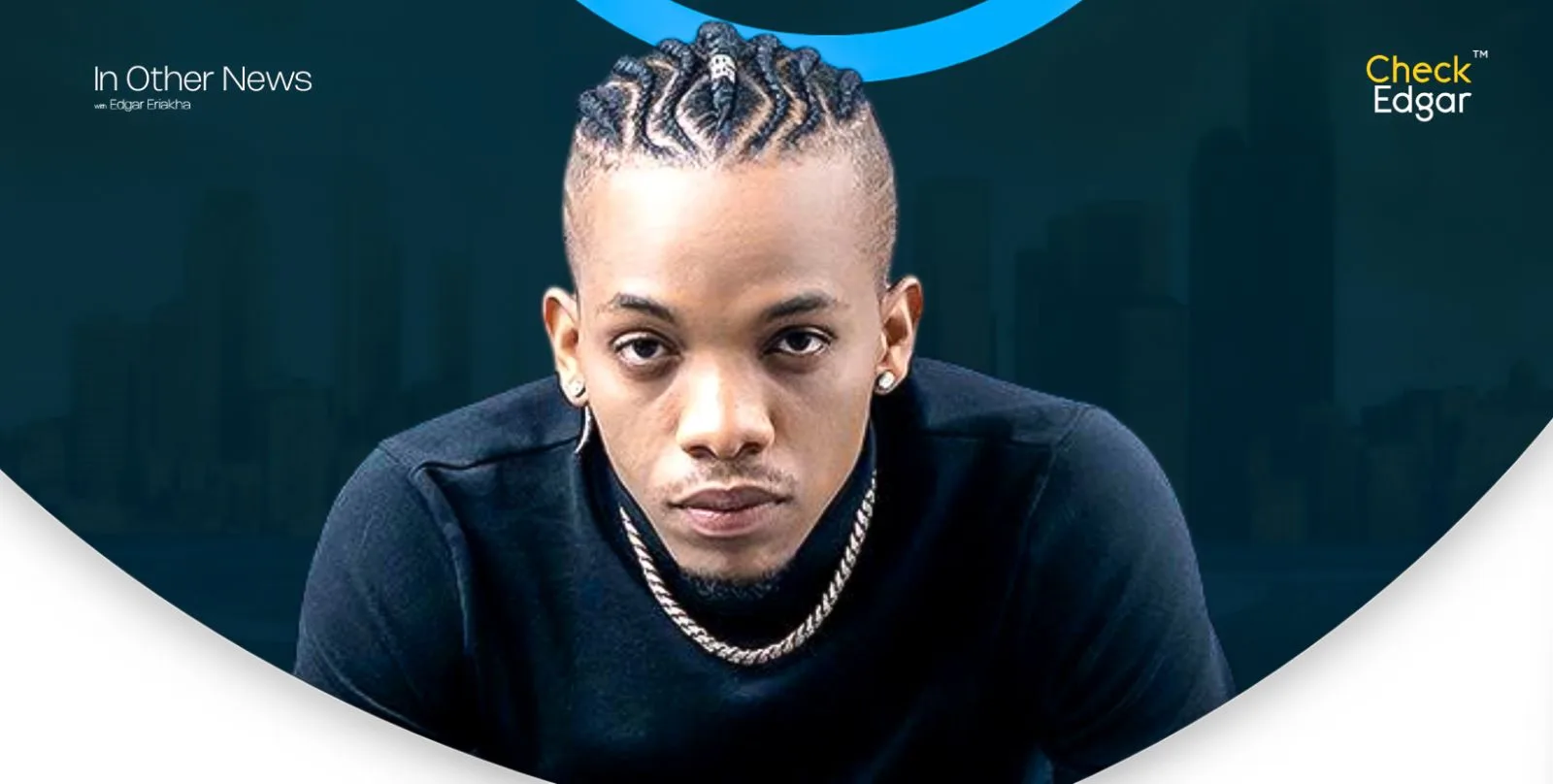 Tekno with braided hair looks directly at the camera, wearing a black shirt and chain necklace.