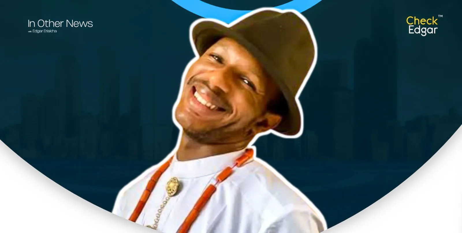 Daniel Regha smiles broadly, wearing a hat and traditional necklace.